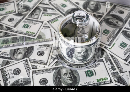 Geld in einem Glasbehälter auf dem Hintergrund der hundert-Dollar-Scheine. Falschgeld. Stockfoto