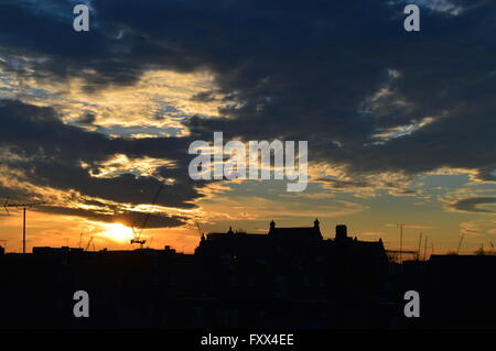 Sonnenaufgang über einer urbanen Skyline von London in Primrose Hill.  Dramatischer Himmel mit Silhouetten von Kränen und eine viktorianische Schule Stockfoto