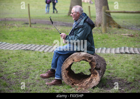 Rentner mit seinem Smartphone auf eine Selfie-Stick im Freien bei Hatchlands Park, Surrey, England, UK Stockfoto