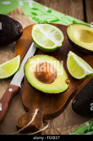 In Scheiben geschnittene frische Avocado und Zitrone Limette auf Schneidebrett auf hölzernen Hintergrund Stockfoto