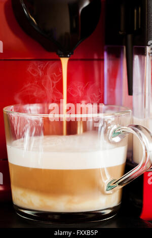 Kaffee Latte im Glas-Tasse von Kaffee-Vollautomat vorbereiten Stockfoto