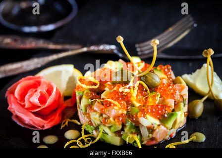 Köstliche rote Kaviar, Lachs und Avocado-Tartar, dunkler Hintergrund Stockfoto