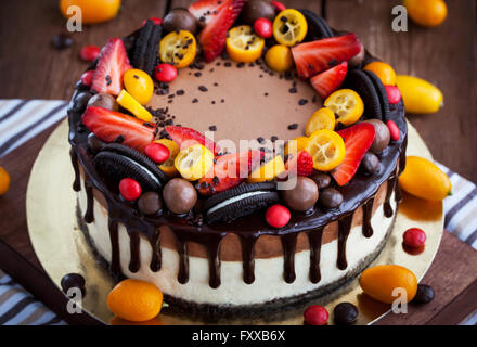 Doppellagige Schokoladen-Käsekuchen mit frischen Erdbeeren, Kumquat und Schokolade verziert Stockfoto