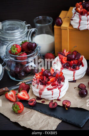 Portion Mini Pavlova Baiser Torte dekoriert mit frischen Erdbeeren und Kirschen Stockfoto