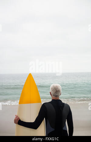 Rückansicht des senior Mann im Anzug mit einem Surfbrett Stockfoto