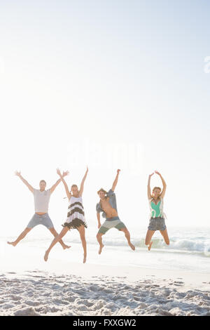 Glückliche Freunde springen am Strand Stockfoto