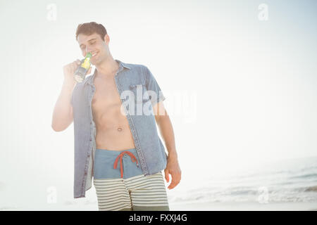 Lächelnd Mann Bier trinken am Strand Stockfoto