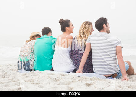 Gruppe von Freunden auf dem Sand sitzen Stockfoto