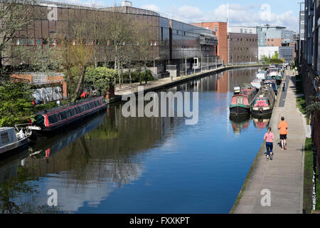 Läufer passieren schmale Boote vertäut am Regents Kanal in der Nähe des Königs, Kings Cross, London, England, UK Stockfoto