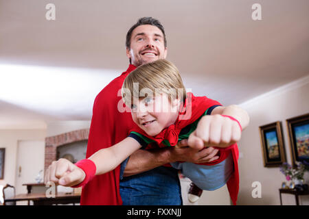 Vater und Sohn, die vorgibt, Superheld im Wohnzimmer Stockfoto