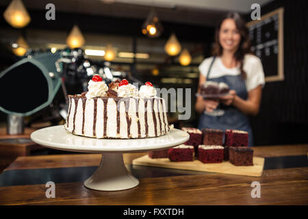 Lächelnde Barista Halteplatte mit Kuchen Stockfoto