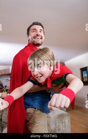 Vater und Sohn, die vorgibt, Superheld im Wohnzimmer Stockfoto