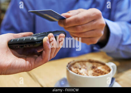 Kunden mit kontaktloses Bezahlen In Coffee-Shop Stockfoto