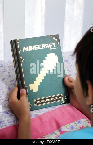 Kleiner Junge liest Minecraft Buch Stockfoto