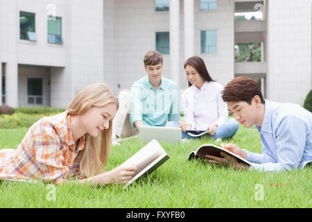 Internationale Studierende und inländische Studierende in College studieren zusammen sitzen und liegen auf einer Wiese auf dem campus Stockfoto