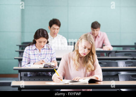 Vier Studenten, darunter internationale und inländische Studenten konzentrieren sich auf das Studium in einem Klassenzimmer Stockfoto