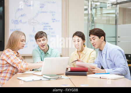 Internationale Studierende und inländische Schüler in der Schule sitzen rund um Schreibtisch studieren gemeinsam im Klassenzimmer für globales Lernen Stockfoto
