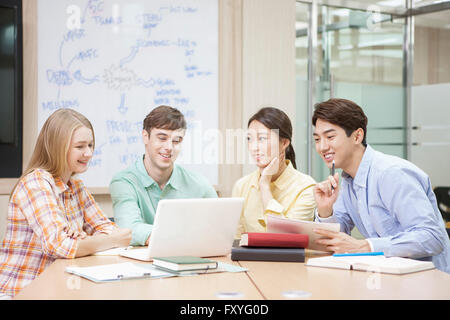 Internationale Studierende und inländische Schüler in der Schule sitzen rund um Schreibtisch studieren gemeinsam im Klassenzimmer für globales Lernen Stockfoto
