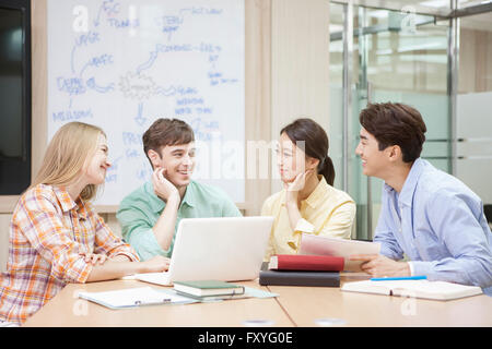 Internationale Studierende und inländische Schüler in der Schule sitzen rund um Schreibtisch studieren gemeinsam im Klassenzimmer für globales Lernen Stockfoto