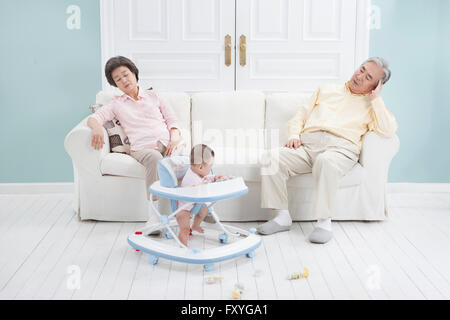 Großeltern sitzen auf einem Sofa-Gefühl müde der Betreuung eines Kindes Stockfoto