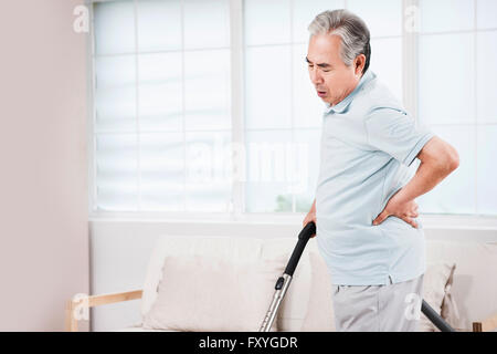 Senior woman Gefühl Schmerz auf seine Taille während den Boden absaugen Stockfoto