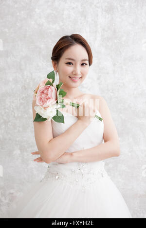 Braut hält Blumenstrauss in ihr Hände starrte nach vorne mit einem Lächeln Stockfoto