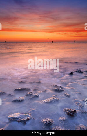 Ein Sandstrand mit Felsen in Zeeland, Niederlande. Am Sonnenuntergang fotografiert. Stockfoto