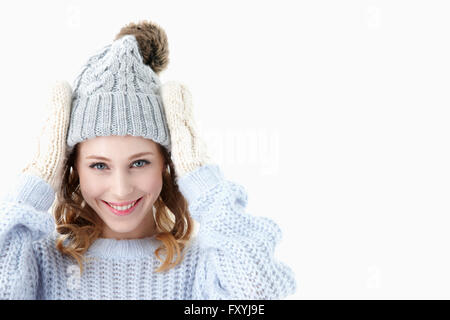 Frau in Winterkleidung berühren ihren Hut mit einem Lächeln Stockfoto