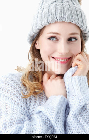 Frau in Winterkleidung greifen die Nackenlinie der ihren Pullover und lächelnd Stockfoto