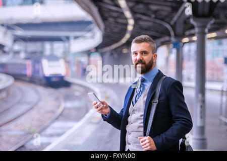 Hipster Geschäftsmann mit Smartphone, warten auf den Zug platfo Stockfoto