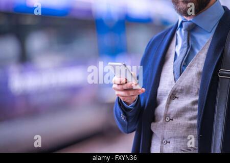 Nicht erkennbare Geschäftsmann mit Smartphone, warten auf den Zug Stockfoto