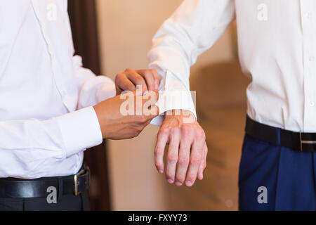 Brautführer hilft Bräutigam auf Manschettenknöpfe Nahaufnahme Stockfoto