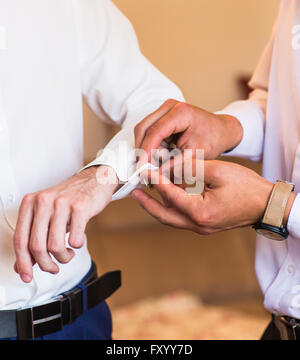 Brautführer hilft Bräutigam auf Manschettenknöpfe hautnah Stockfoto