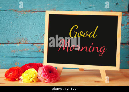 Tafel mit dem Ausdruck guten Morgen neben frischen Blumen darauf geschrieben. Stockfoto