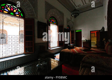 Ein Schlafzimmer Innenraum eines traditionellen Riads in Fes, Marokko. Fleck verglasten Fenster und Licht vom Hof füllen den dunklen Raum. Stockfoto