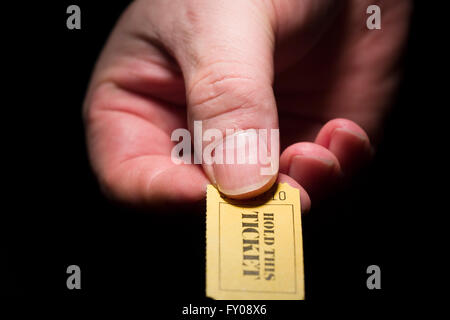 Ein Mann rechten Hand ein gelbes 7-stellige Ticket markiert mit den Worten "THIS TICKET halten" in schwarzer Tinte Stockfoto