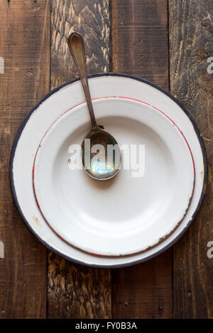 leere Suppenschüssel mit Löffel auf alten hölzernen Hintergrund Stockfoto