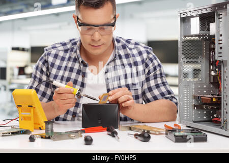 Young-PC-Techniker arbeiten mit Lötkolben auf einem Computerchip im Rahmen eines Workshops Stockfoto