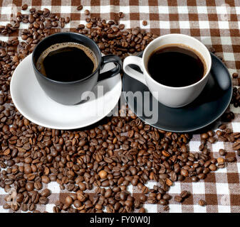 Zwei Tassen Kaffee und Kaffeebohnen auf einem karierten Tuch Stockfoto