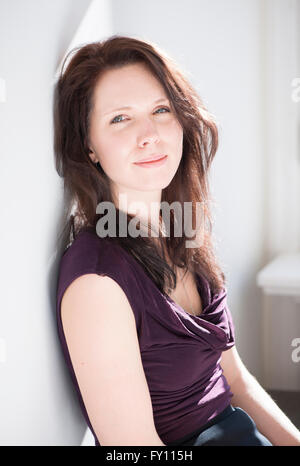 Frau sitzt in Wohngebäude. Lebensstil-Bild der jungen Frau zeigt stolz, Entspannung und Zufriedenheit. Stockfoto