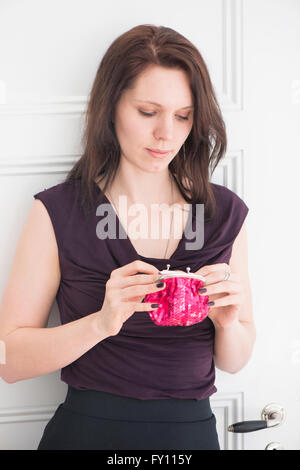 Porträt der Frau hält eine rote Geldbörse Lifestyle Bild der jungen Frau im schwarzen Kleid Konzept des Einkaufens Eigenheim-Finanzierung und Stockfoto