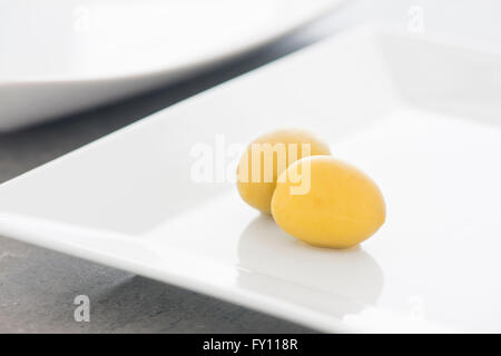 Grüne Oliven auf weißen Teller in Nahaufnahme. Still-Leben Foto von Vorspeise oder Snack. Stockfoto