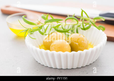 Grüne Oliven in Olivenöl und einem Zweig frischer Thymian. Still-Leben Foto von Vorspeise oder Snack. Stockfoto