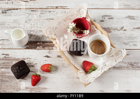 Schokoladen-Muffins, Kaffee, Erdbeeren, eine Vase mit weißen Blüten. Hellen Holz rustikal Hintergrund Stockfoto