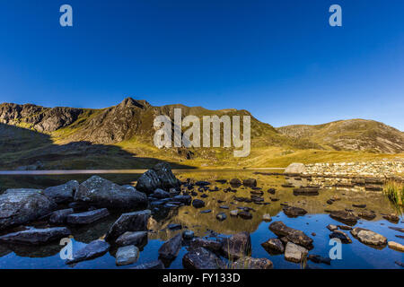 Am frühen Morgensonne beginnt Llyn Idwal und der Glyderau-Reihe von Gipfeln in Snowdonia, Nordwales ans Licht. Stockfoto