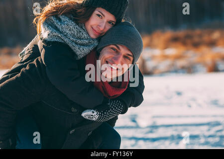 Porträt von glücklicher Mann Frau Huckepack Fahrt einzuräumen, im winter Stockfoto