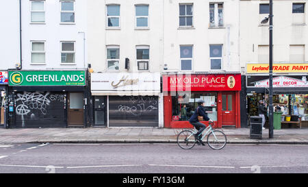 Typische Straße mit kleinen unabhängigen Einzelhandel Geschäfte im Londoner East End. Radfahrer vorbei auf der Straße. Stockfoto