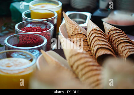 Eistüten und verschiedene aromatisierte Sirupe im store Stockfoto