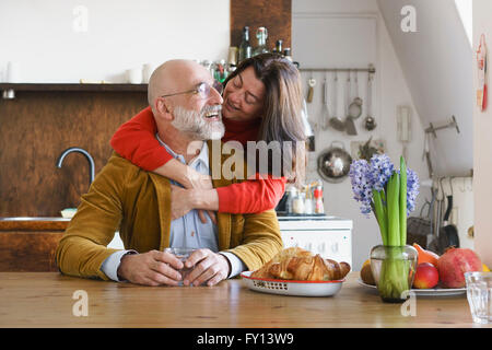 Glückliches Paar umarmt und lächelnd vom Tisch zu Hause Stockfoto