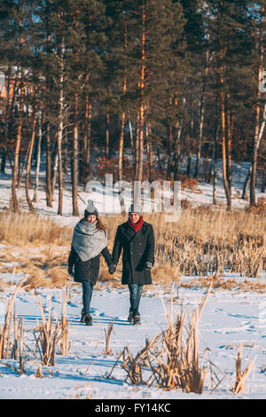 Junges Paar Hand in Hand während des Gehens auf Schnee überdachten Bereich Stockfoto